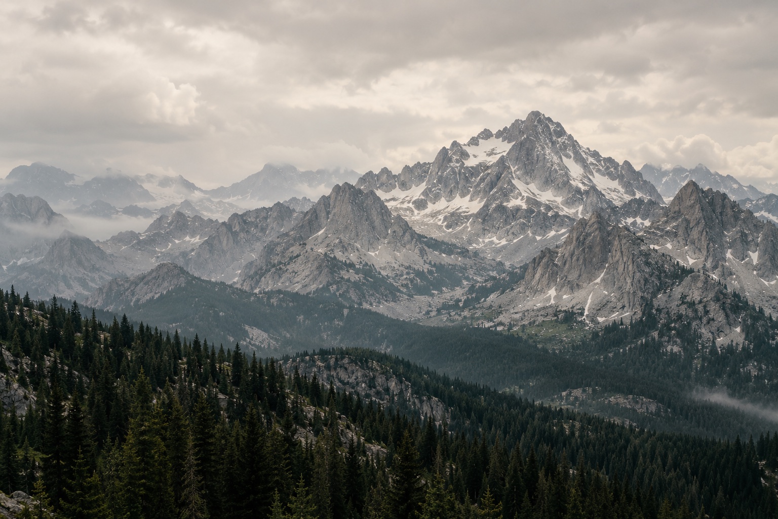 Layered granite peaks above a dark forest in the Rocky Mountains